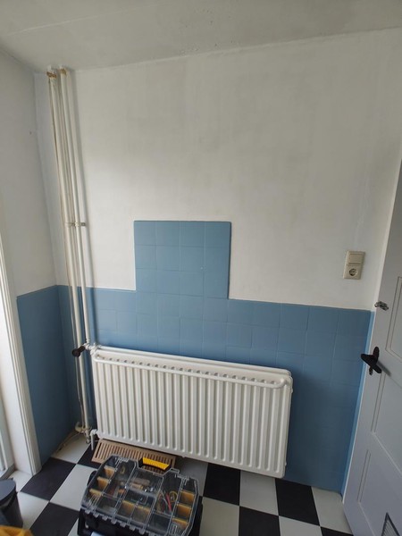 De radiator, de deur naar het droogplat, en de deur naar de overloop.